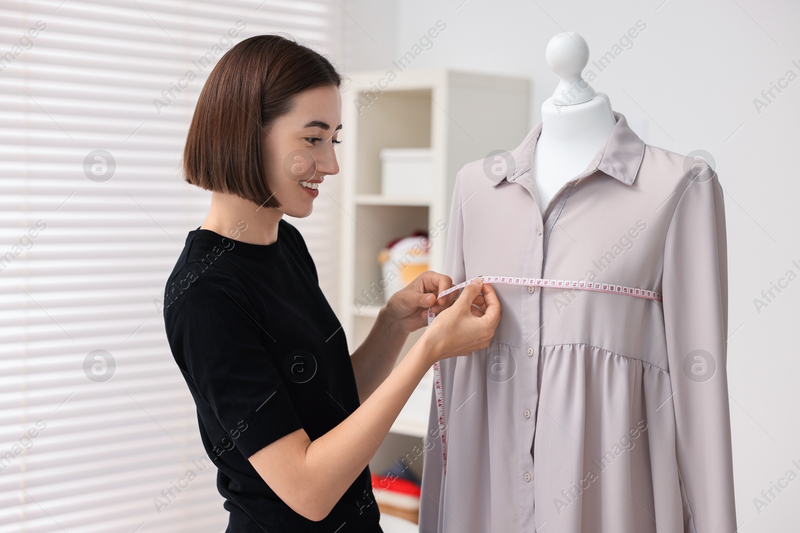 Photo of Fashion designer with measuring tape working in workshop