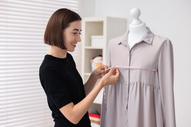 Fashion designer with measuring tape working in workshop