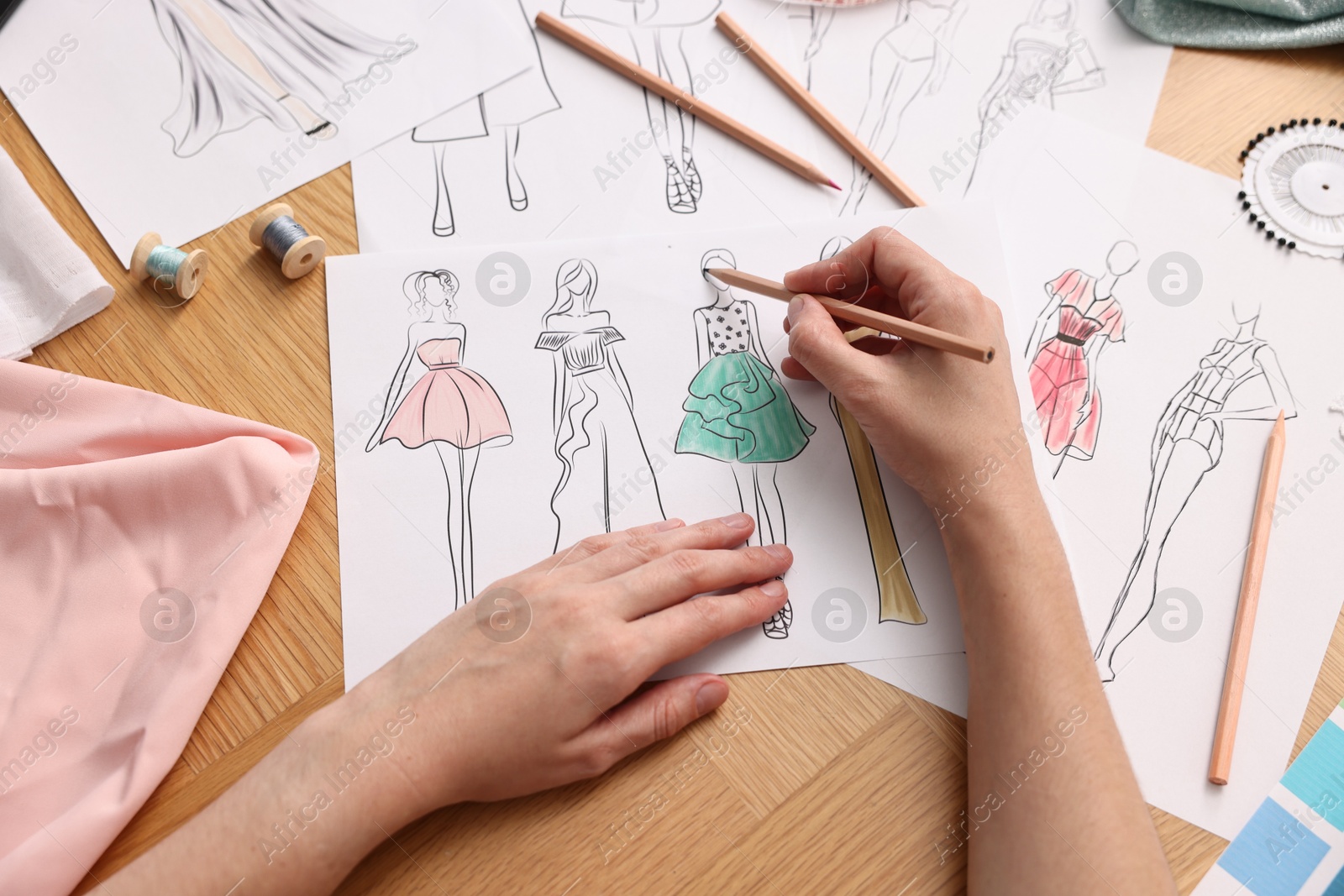 Photo of Fashion designer drawing sketch of beautiful dress at wooden table, top view