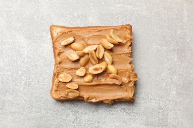 Photo of Tasty sandwich with peanut butter and nuts on grey textured table, top view