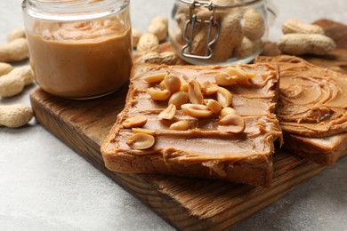 Photo of Tasty sandwiches with peanut butter and nuts on grey textured table, closeup