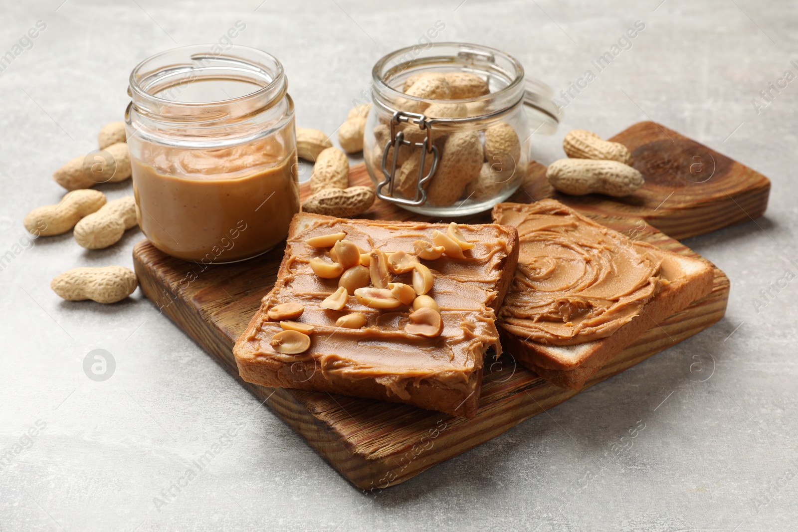 Photo of Tasty sandwiches with peanut butter and nuts on grey textured table, closeup