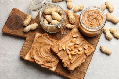 Photo of Tasty sandwiches with peanut butter and nuts on grey textured table, flat lay