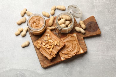 Photo of Tasty sandwiches with peanut butter and nuts on grey textured table, flat lay