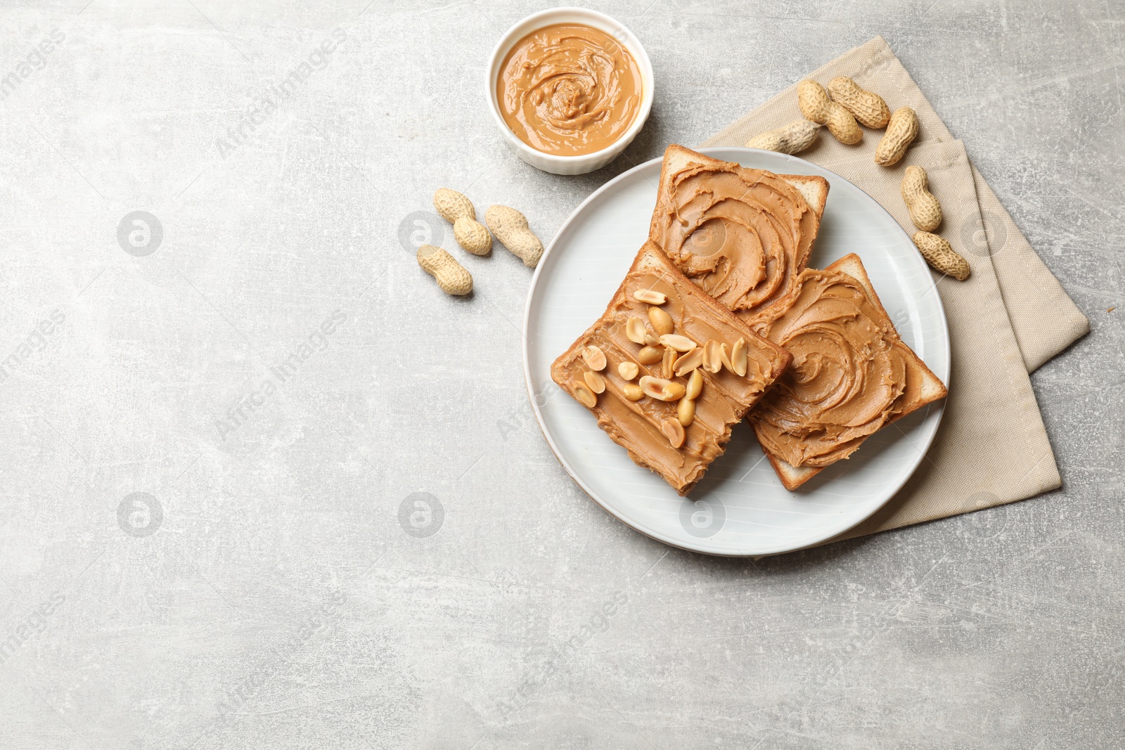 Photo of Tasty sandwiches with peanut butter and nuts on grey textured table, flat lay. Space for text