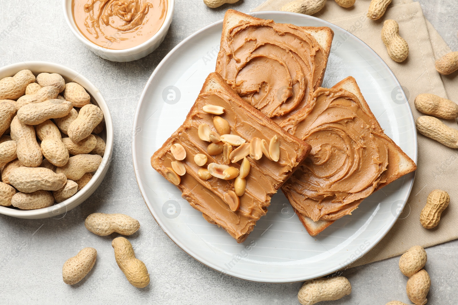 Photo of Tasty sandwiches with peanut butter and nuts on grey textured table, flat lay