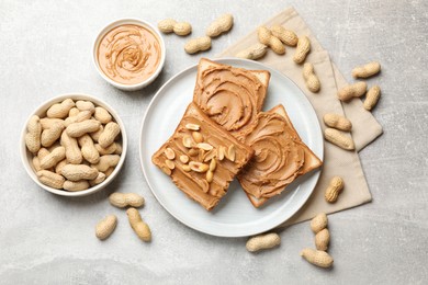 Photo of Tasty sandwiches with peanut butter and nuts on grey textured table, flat lay