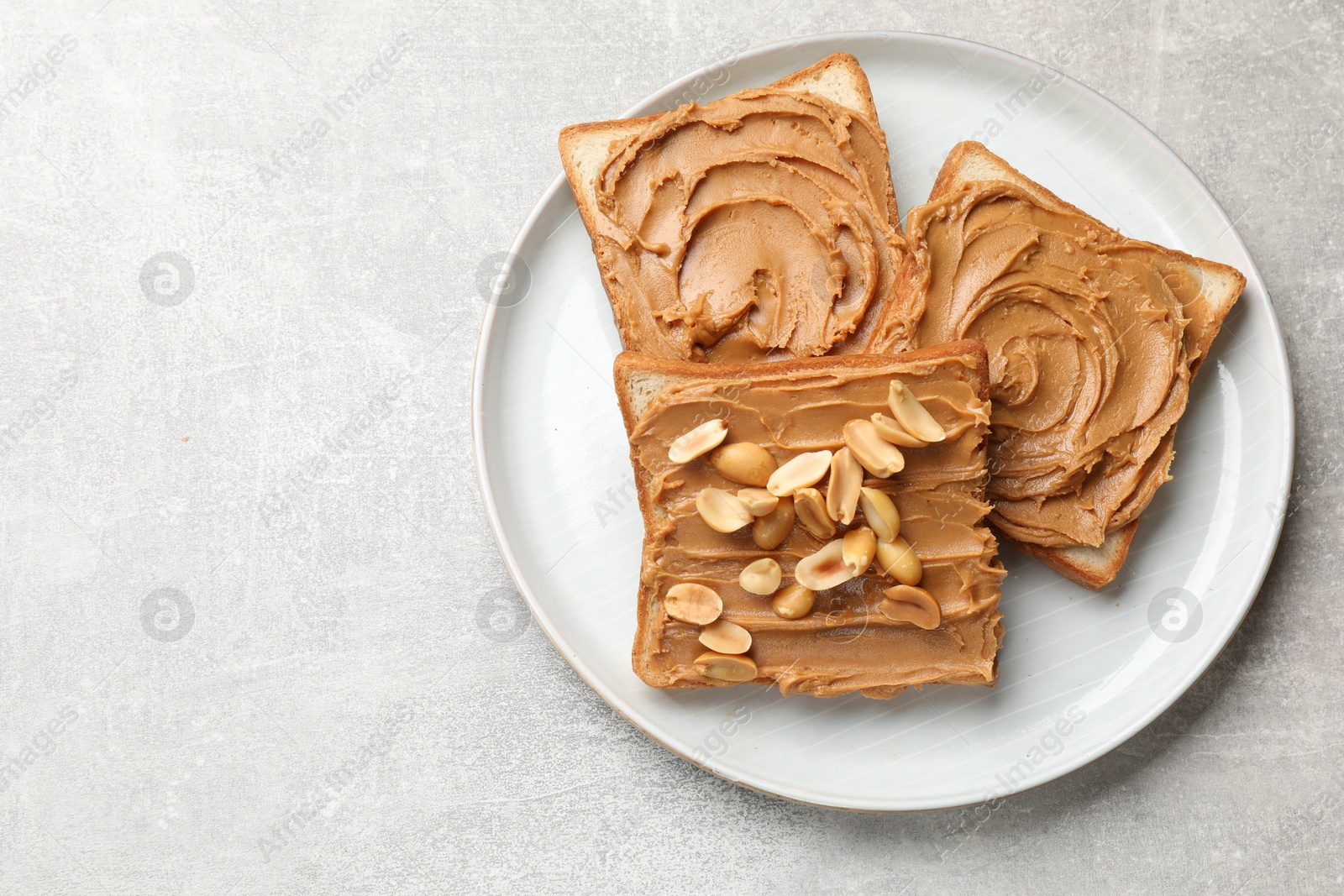 Photo of Tasty sandwiches with peanut butter and nuts on grey textured table, top view. Space for text