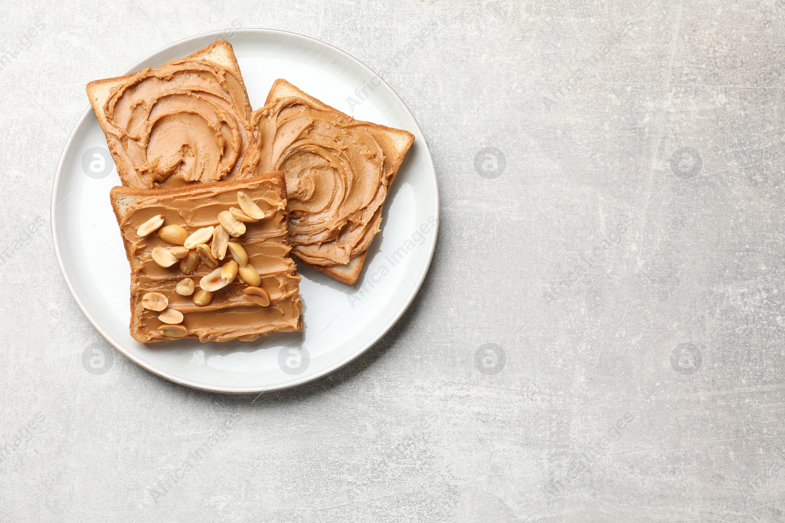 Photo of Tasty sandwiches with peanut butter and nuts on grey textured table, top view. Space for text