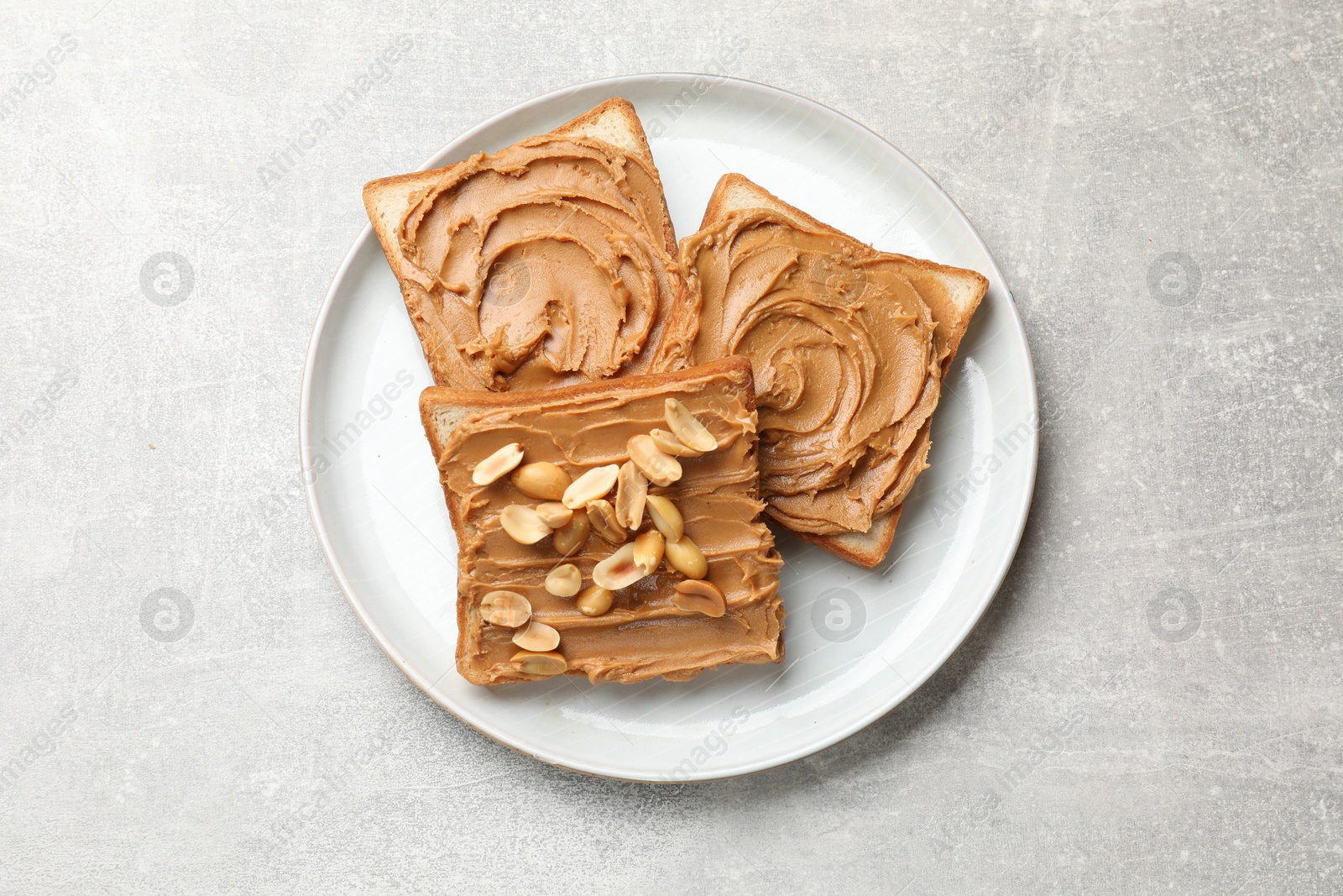 Photo of Tasty sandwiches with peanut butter and nuts on grey textured table, top view