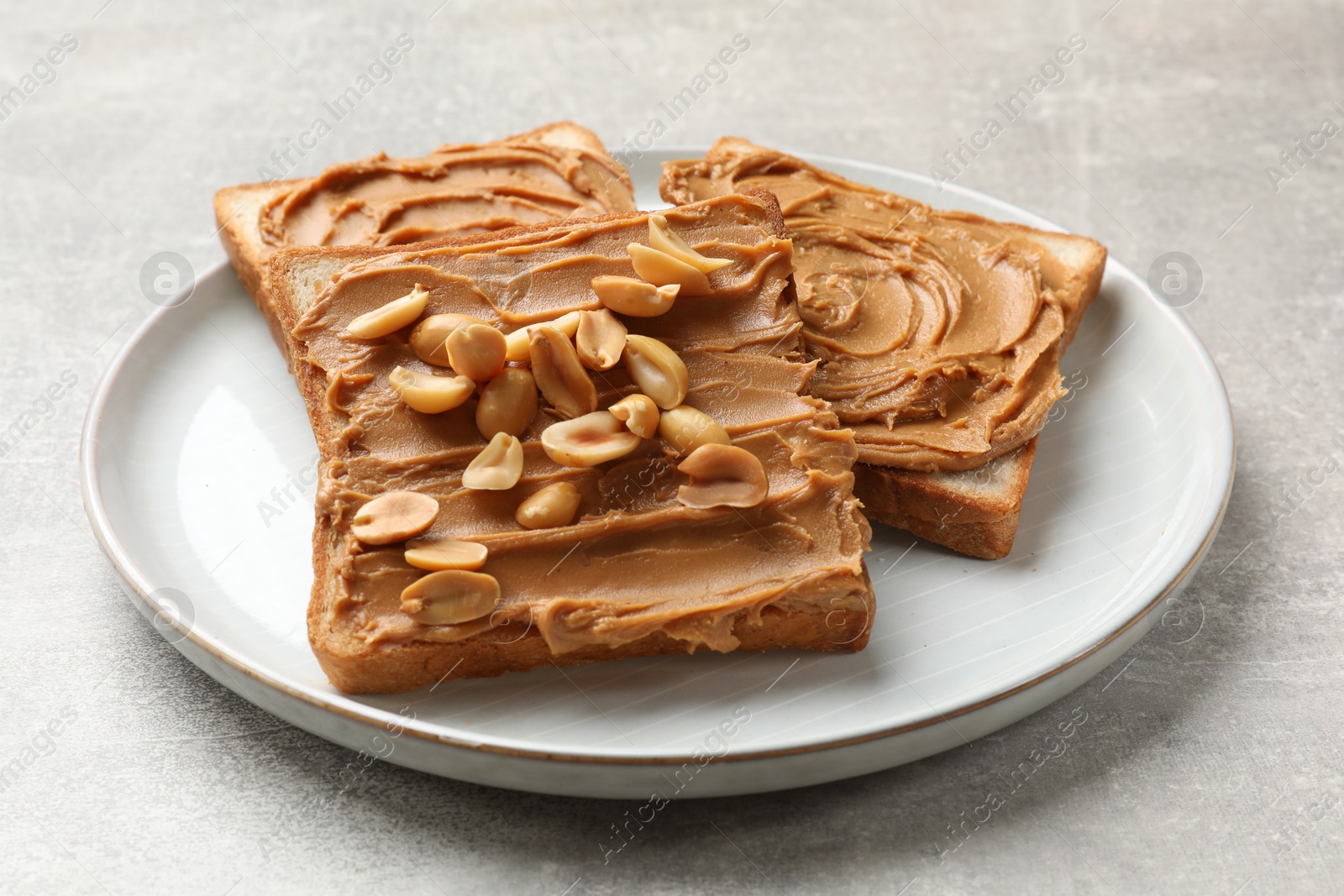 Photo of Tasty sandwiches with peanut butter and nuts on grey textured table, closeup