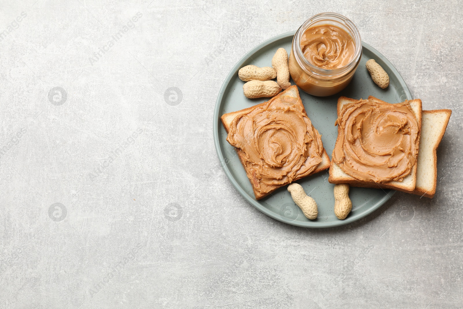 Photo of Tasty sandwiches with peanut butter and nuts on grey textured table, top view. Space for text