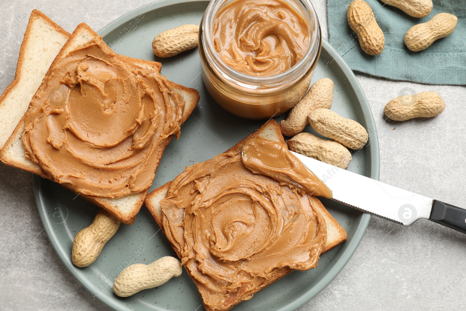 Photo of Tasty sandwiches with peanut butter and nuts on grey textured table, flat lay