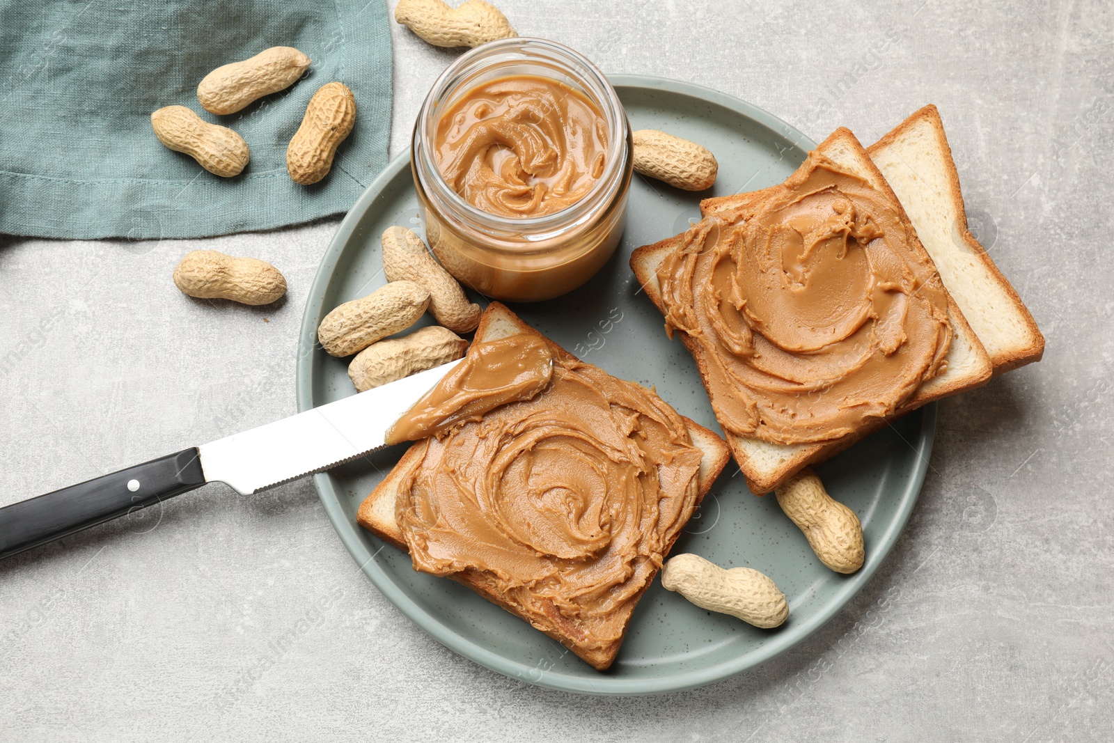 Photo of Tasty sandwiches with peanut butter and nuts on grey textured table, flat lay