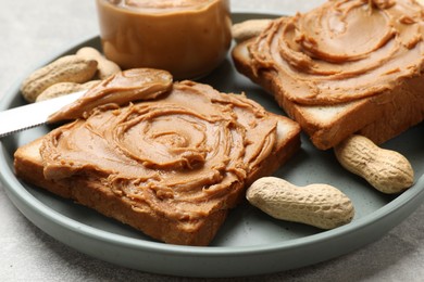 Photo of Tasty sandwiches with peanut butter and nuts on grey textured table, closeup