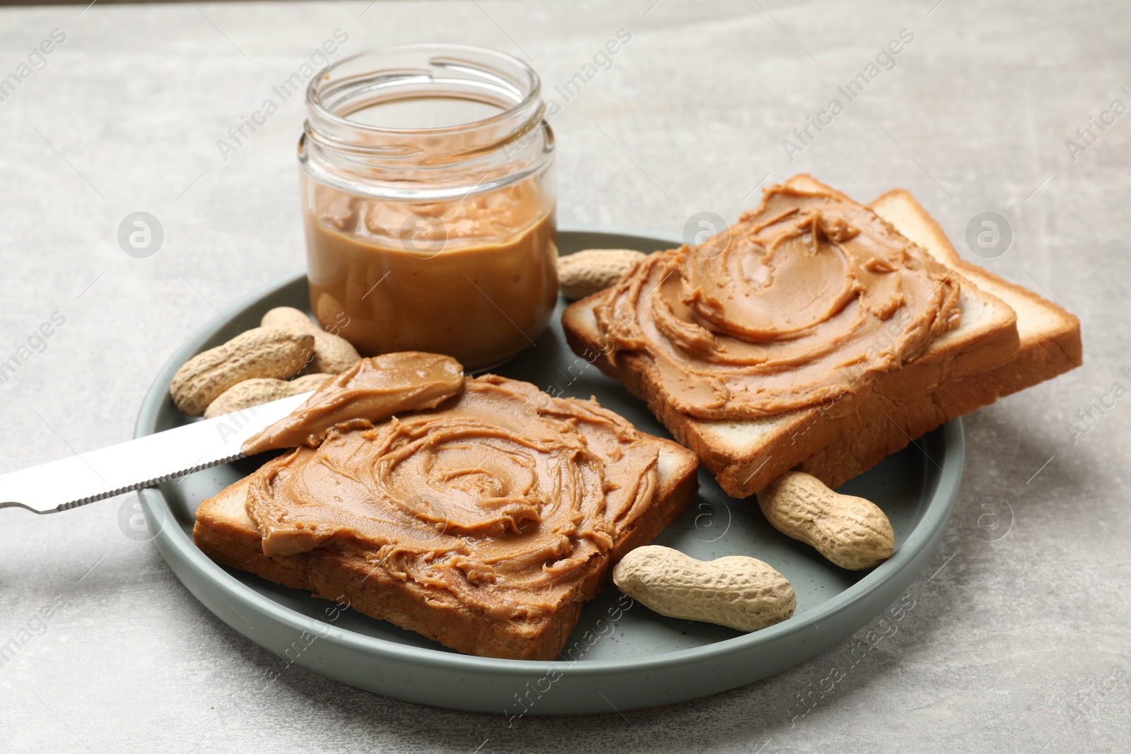 Photo of Tasty sandwiches with peanut butter and nuts on grey textured table, closeup