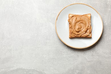 Photo of Tasty sandwich with peanut butter and nuts on grey textured table, top view. Space for text