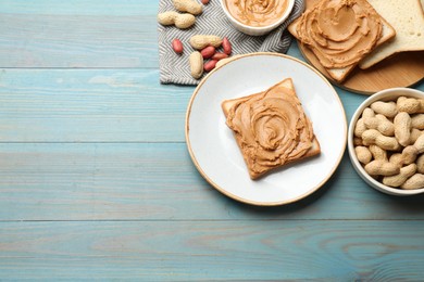 Photo of Tasty sandwiches with peanut butter and nuts on light blue wooden table, flat lay. Space for text