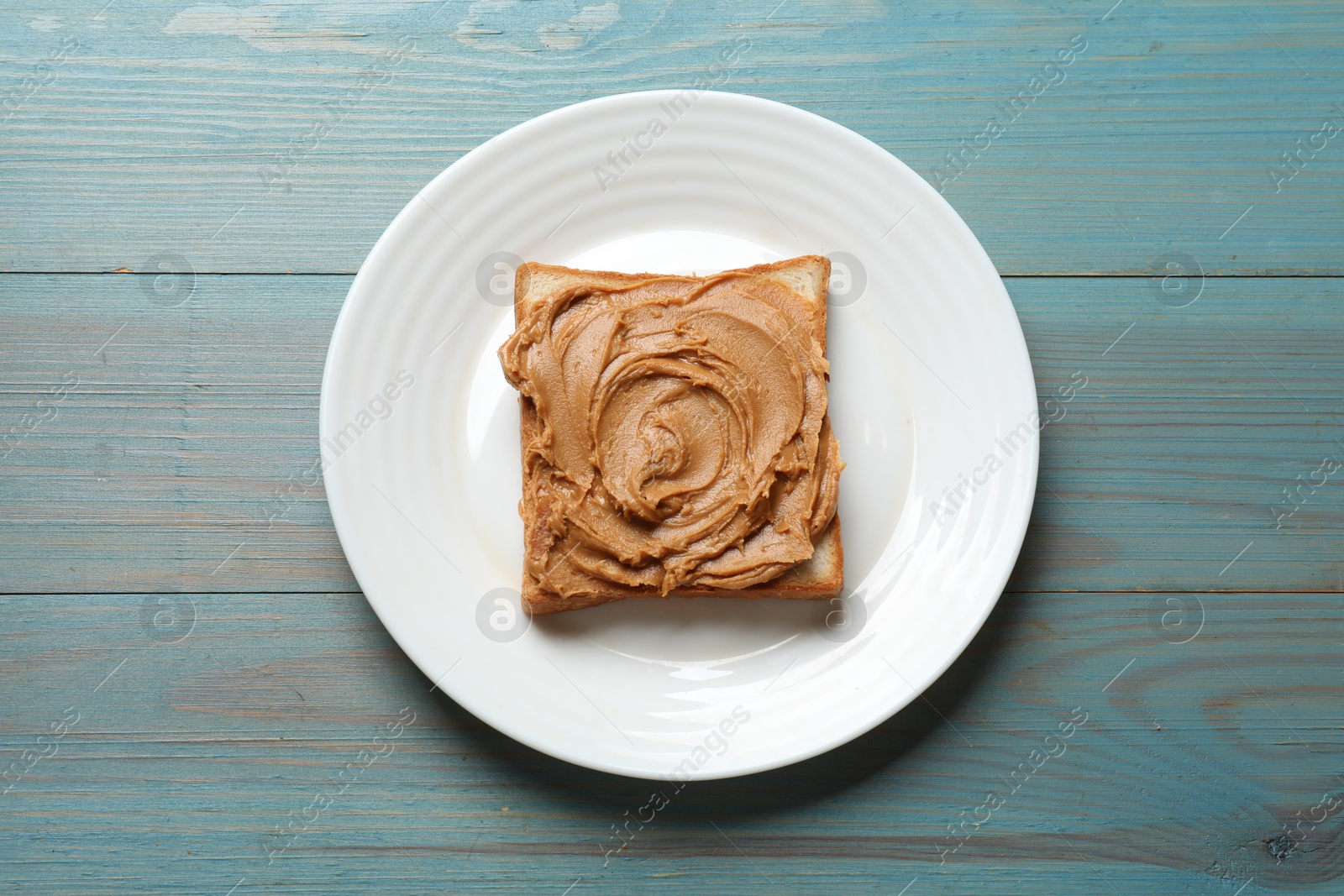 Photo of Tasty sandwich with peanut butter on light blue wooden table, top view