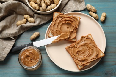 Photo of Tasty sandwiches with peanut butter and nuts on light blue wooden table, flat lay