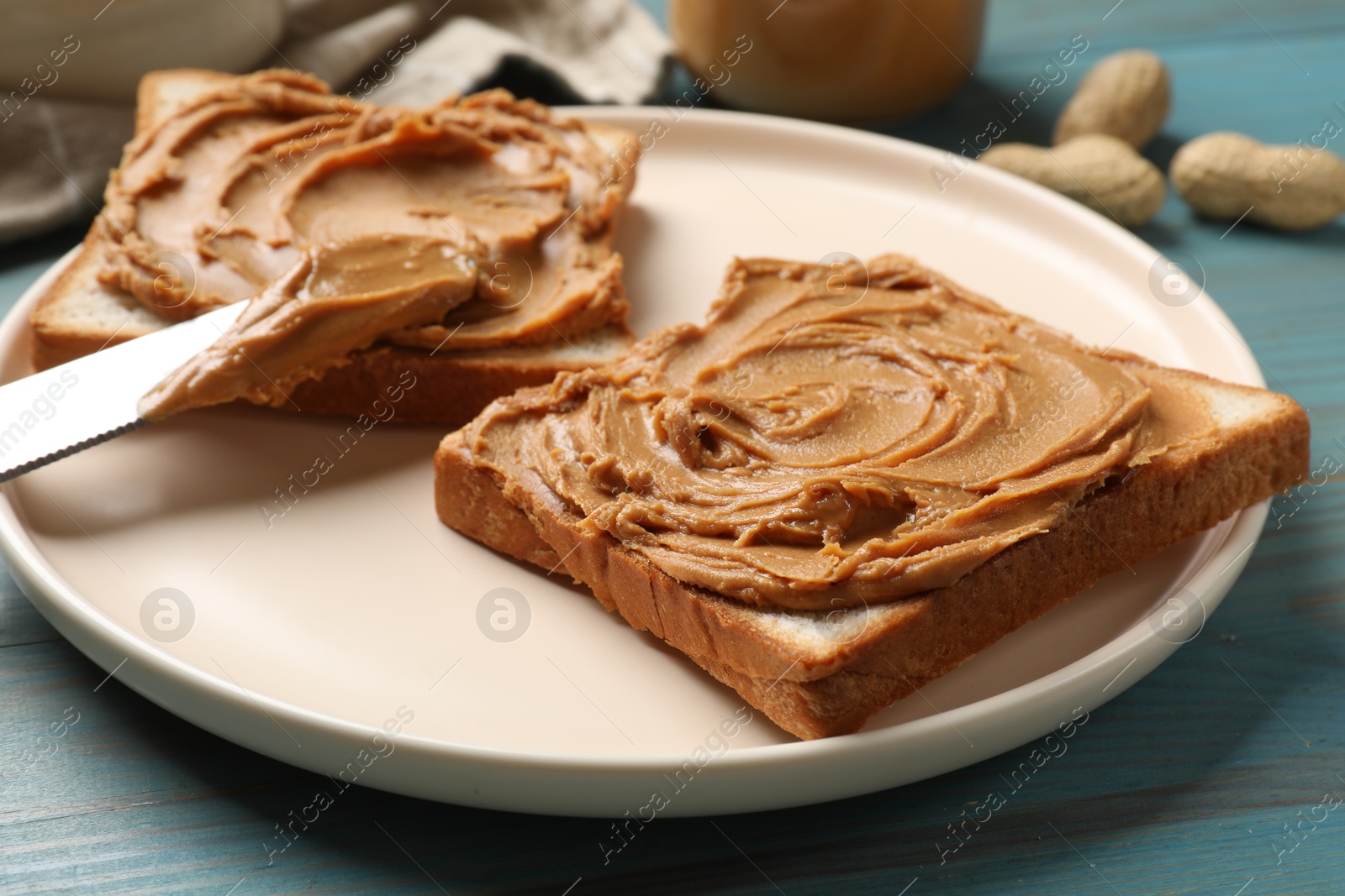 Photo of Tasty sandwiches with peanut butter on light blue wooden table, closeup