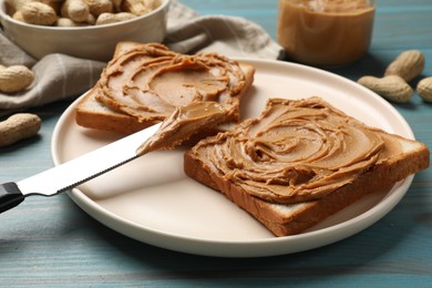 Photo of Tasty sandwiches with peanut butter and nuts on light blue wooden table, closeup