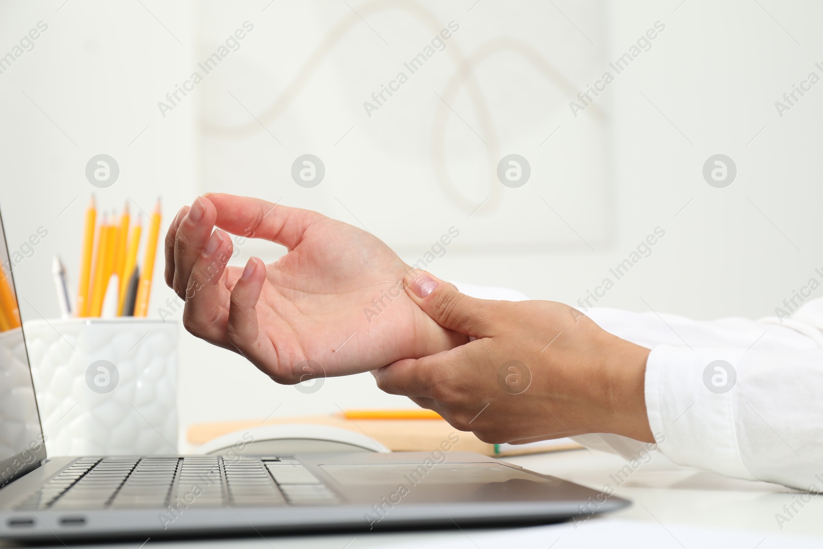 Photo of Carpal tunnel syndrome. Woman suffering from pain in wrist at desk indoors, closeup