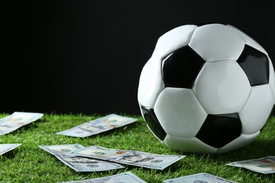 Photo of Soccer ball and dollar banknotes on green grass