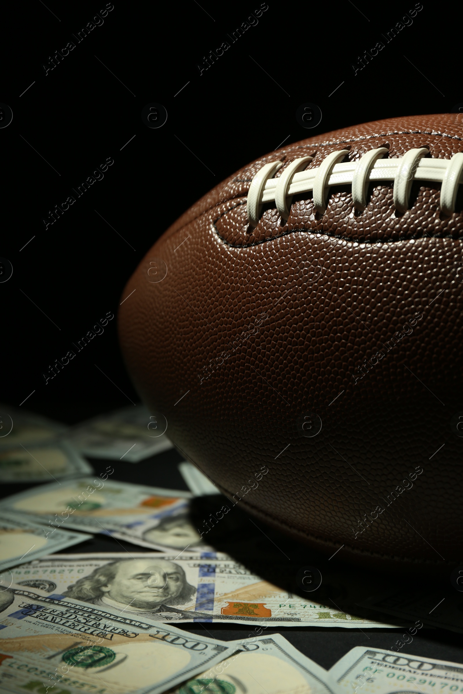 Photo of American football ball and dollar banknotes on table, closeup