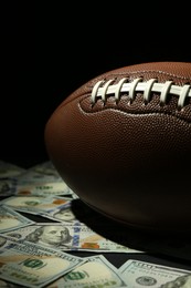 Photo of American football ball and dollar banknotes on table, closeup