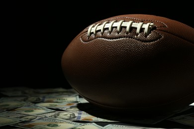 Photo of American football ball and dollar banknotes on table, closeup