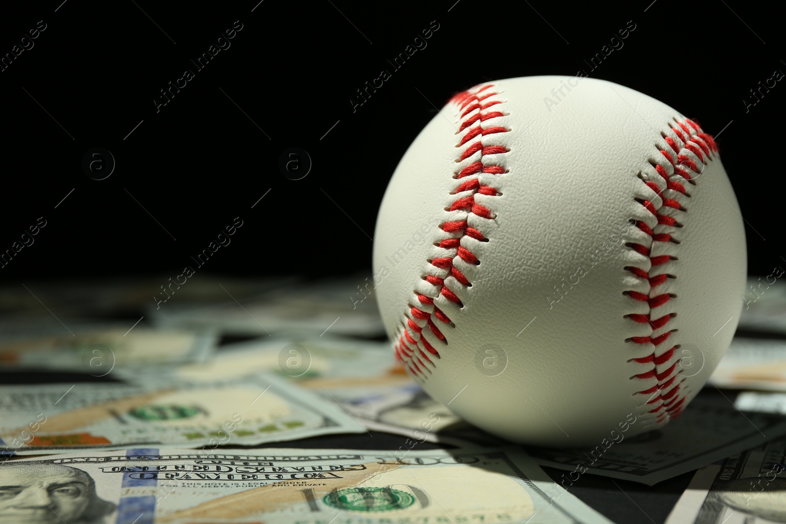 Photo of Baseball ball and dollar banknotes on table, closeup