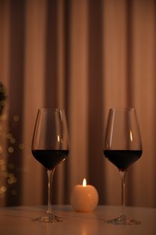 Burning candle and wine in glasses on table indoors