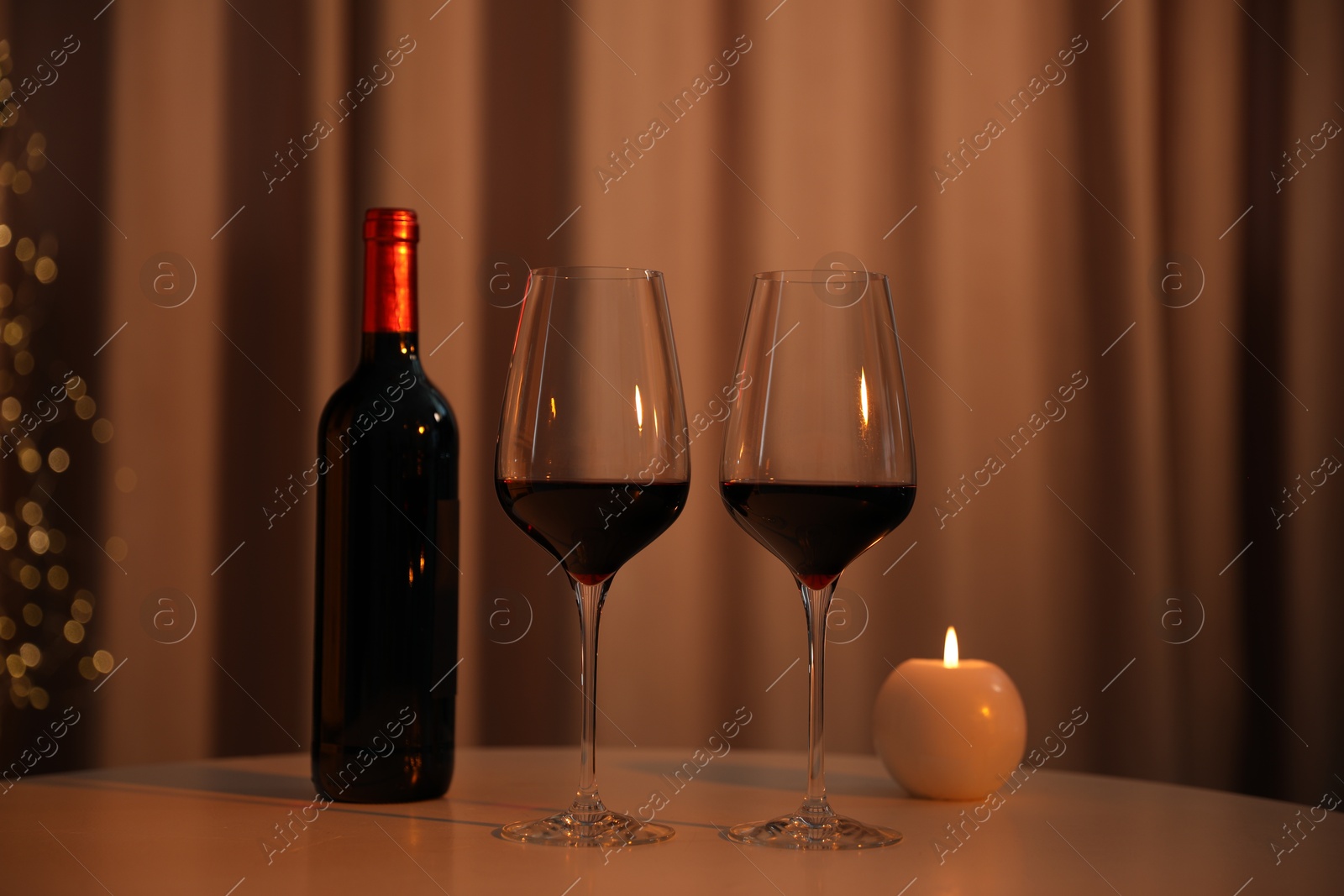 Photo of Burning candle and wine on table indoors