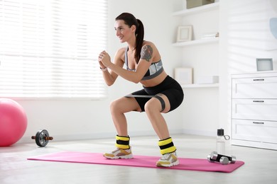 Woman with ankle weights and elastic band training indoors