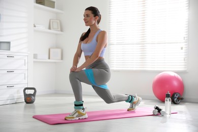 Photo of Woman with ankle weights and elastic band training indoors