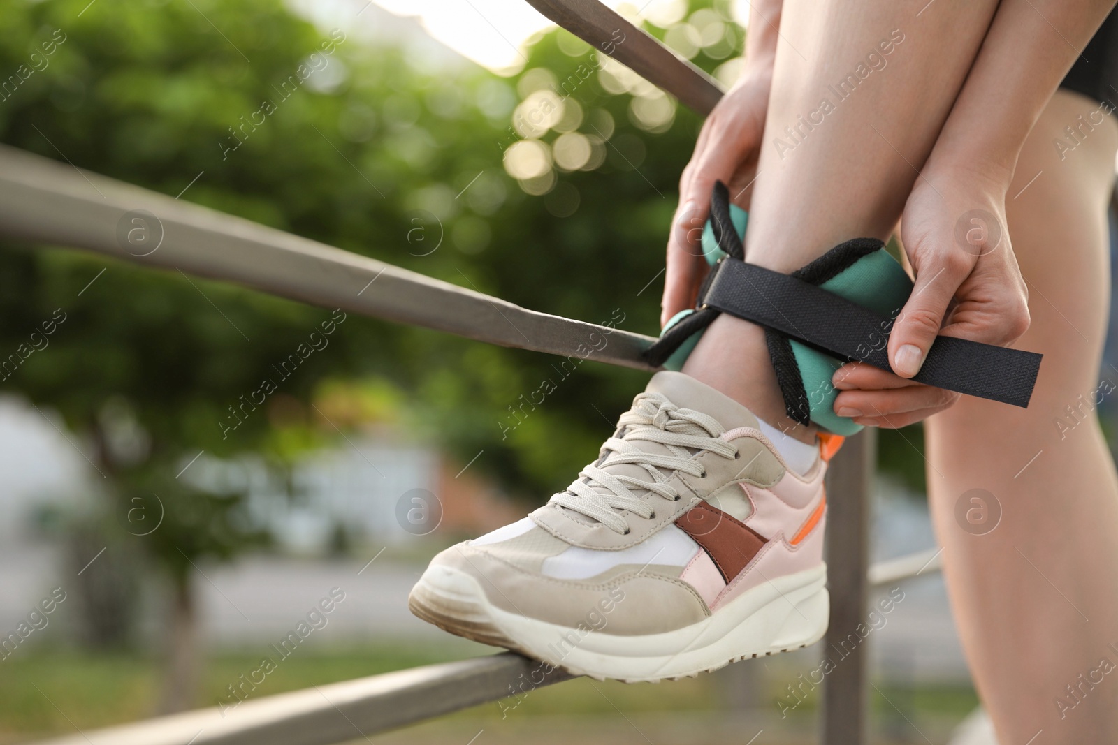 Photo of Woman putting on ankle weight outdoors, closeup