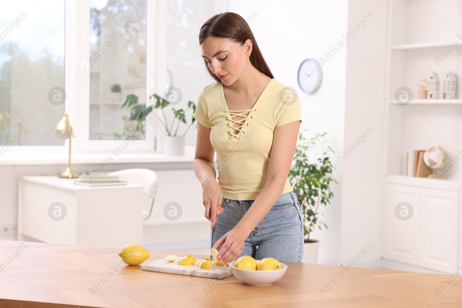 Photo of Making lemon water. Woman cutting fruit at wooden table indoors