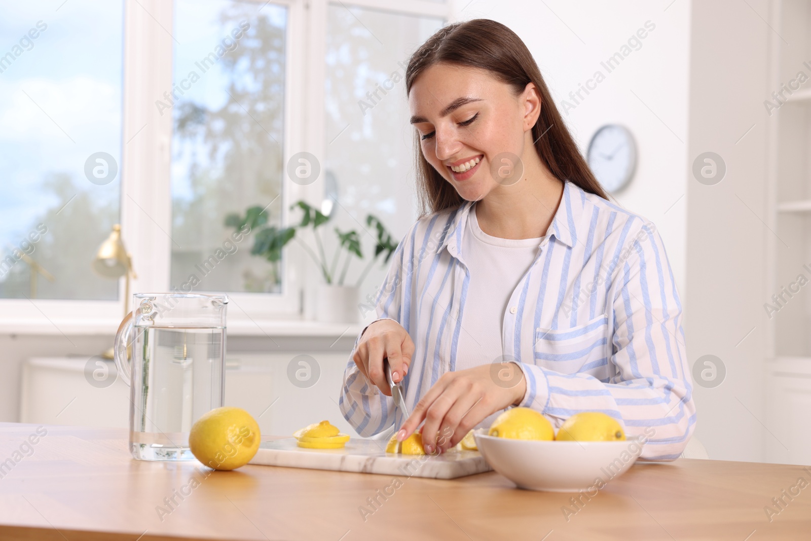 Photo of Making lemon water. Woman cutting fruit at table indoors