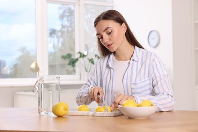 Photo of Making lemon water. Woman cutting fruit at wooden table indoors