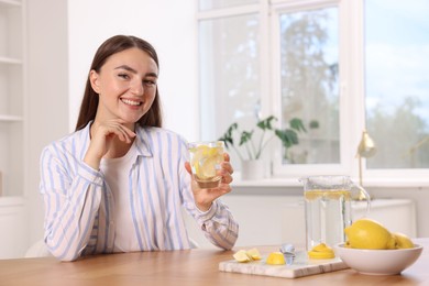 Photo of Woman with glass of lemon water indoors. Space for text