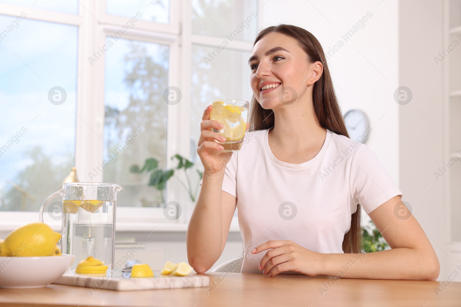 Photo of Woman with glass of lemon water indoors