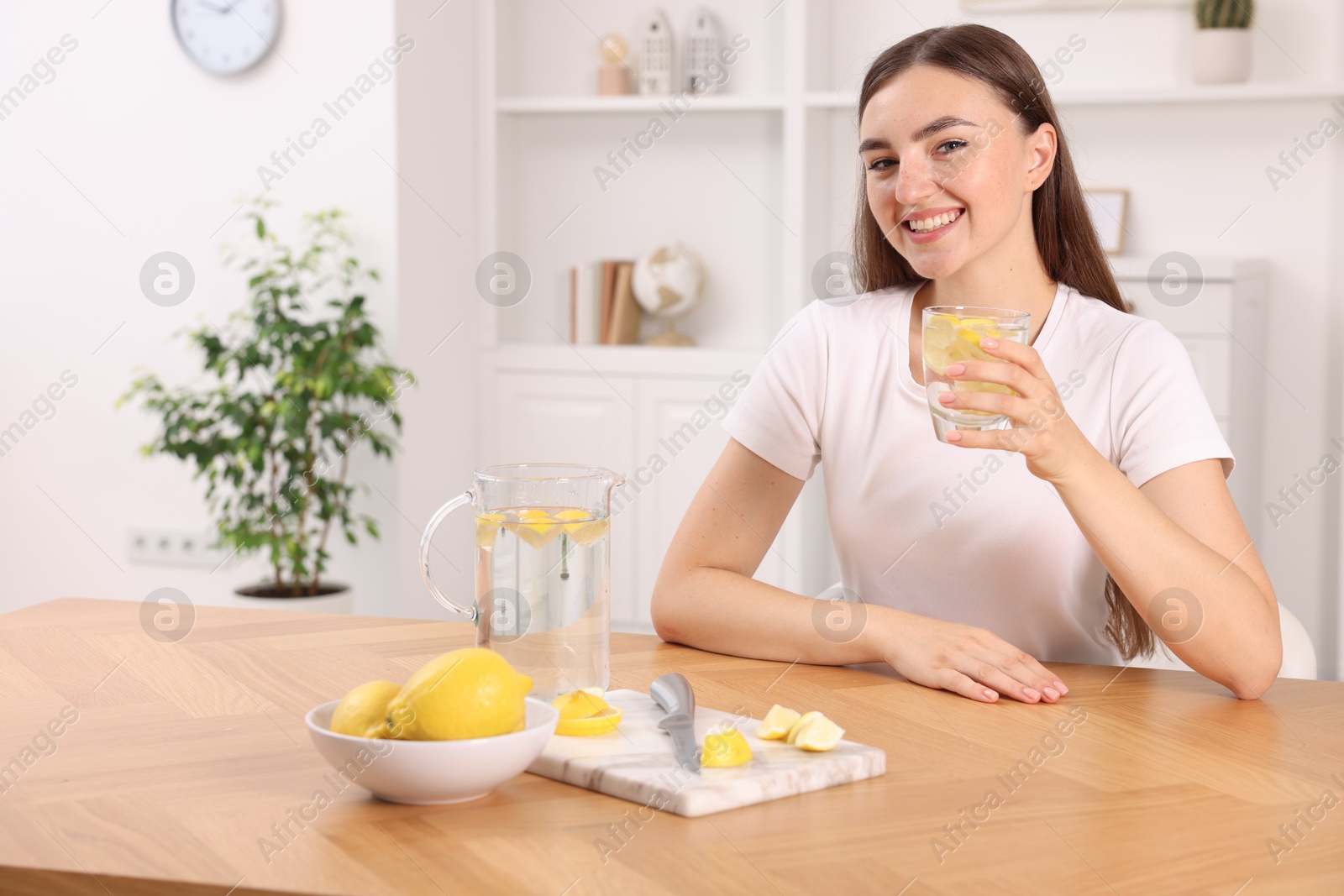 Photo of Woman with glass of lemon water indoors. Space for text