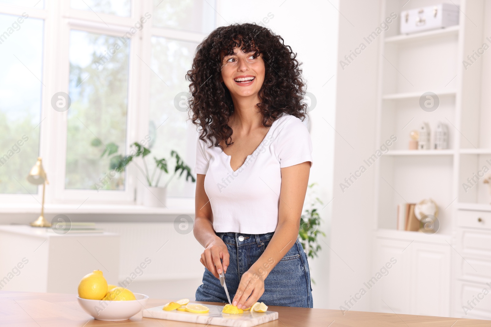 Photo of Making lemon water. Woman cutting fruit at wooden table indoors