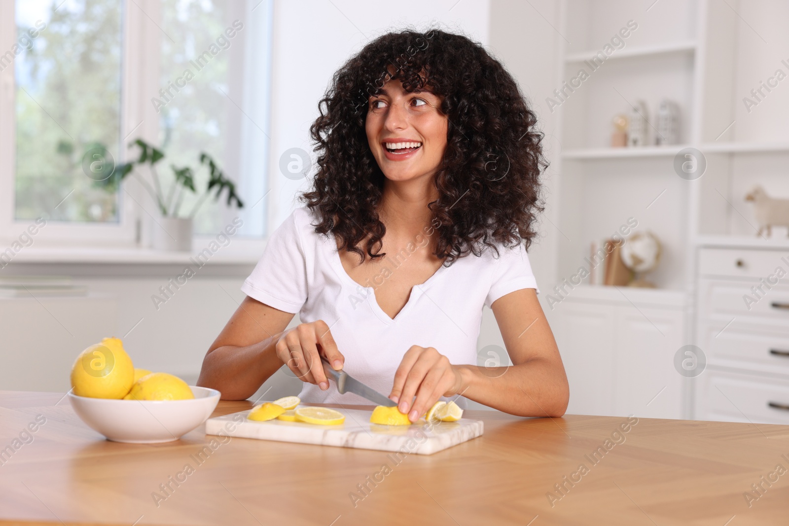 Photo of Making lemon water. Woman cutting fruit at wooden table indoors