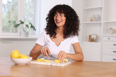 Making lemon water. Woman cutting fruit at wooden table indoors