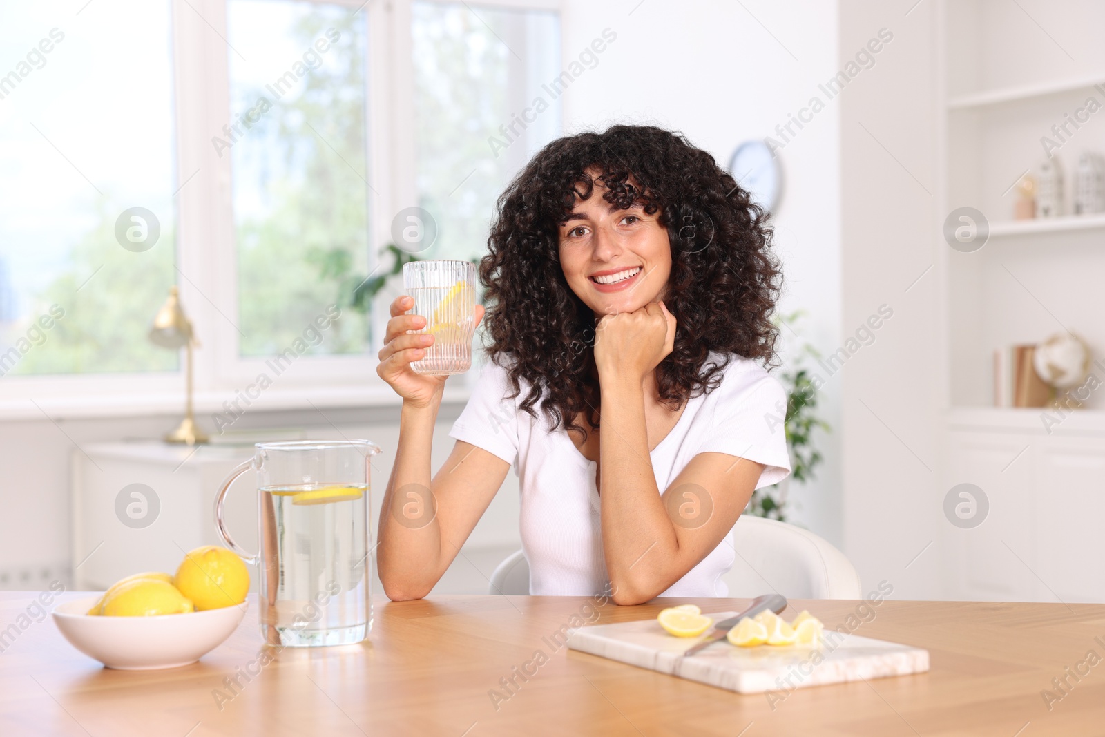 Photo of Woman with glass of lemon water indoors