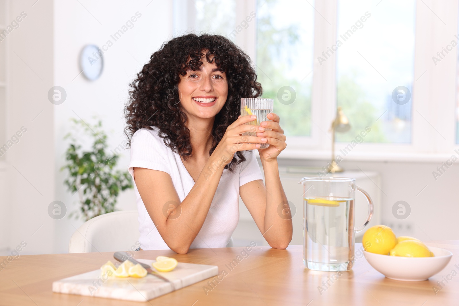 Photo of Woman with glass of lemon water indoors