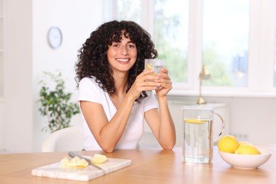 Woman with glass of lemon water indoors