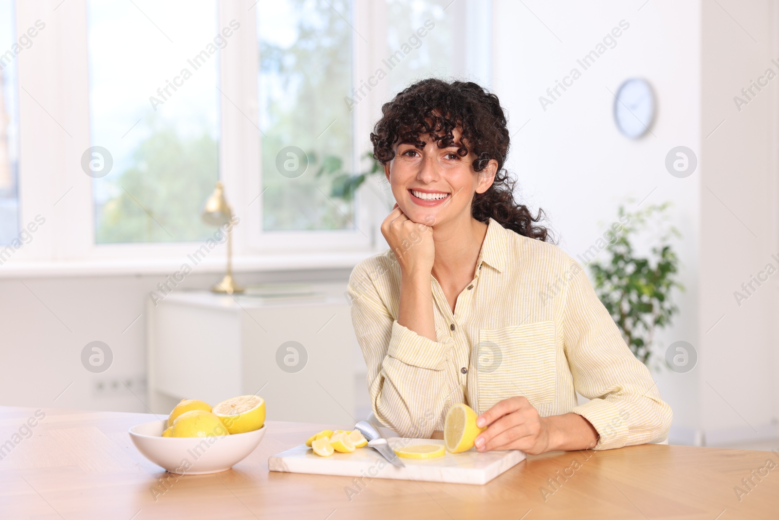 Photo of Woman with cut lemons at table indoors